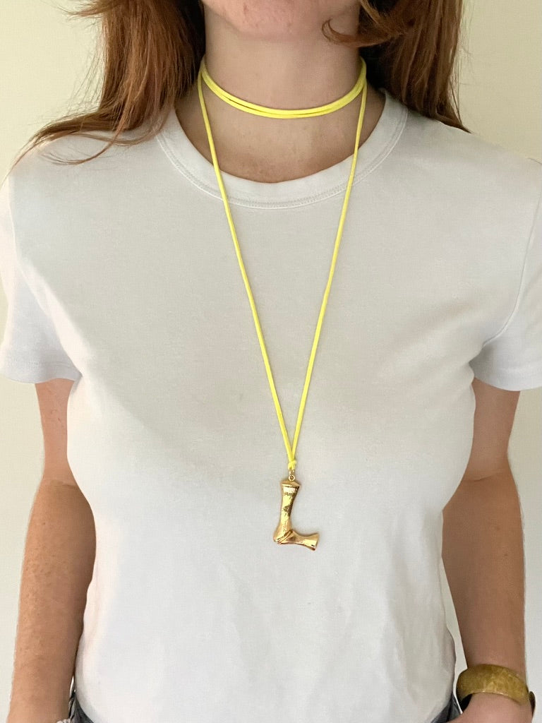 The Clásico by LAZO Collective: gold bamboo-style initial pendant on a maize yellow or azul blue suede tie cord